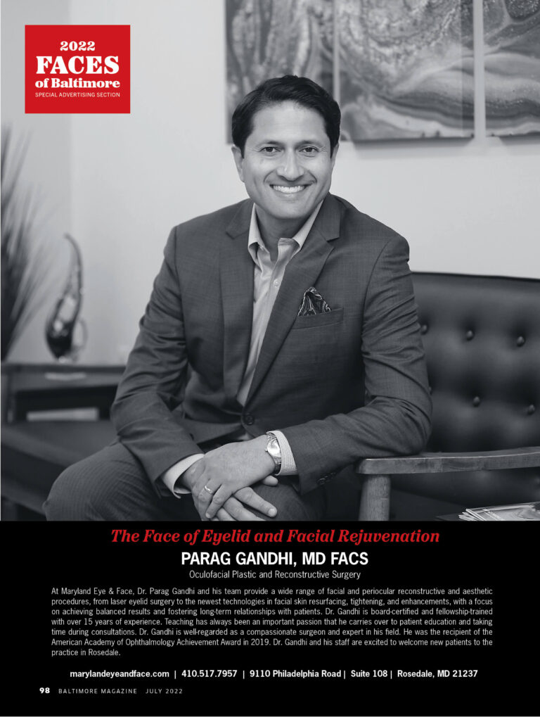 Dr. Parag Gandhi in a suit smiling, seated on a couch in an office setting. Text reads "2022 Faces of Baltimore" and highlights eyelid and facial rejuvenation.