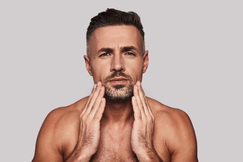 Man touching his face and looking at camera.